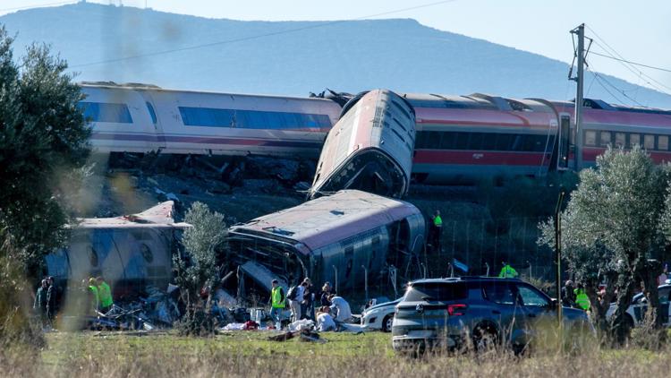 Rescue workers at the scene of a devastating train crash in Spain, with mangled train cars visible